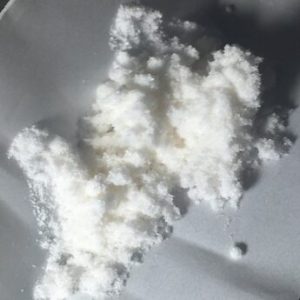 Close-up of a small pile of white crystalline powder on a light-colored surface, representing premium LSD powder.
