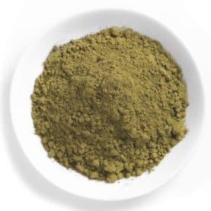 A close-up view of a white bowl filled with fine, green kratom powder, showcasing its textured surface.